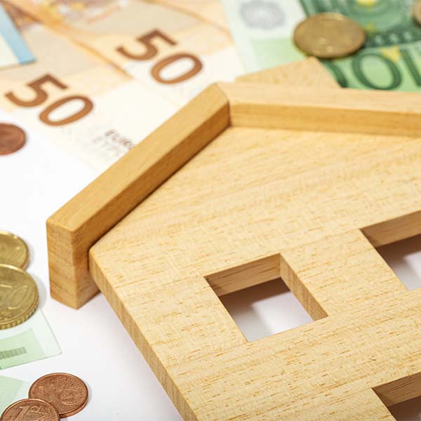 Notas, moedas e uma casa em papel a representar uma herança indivisa